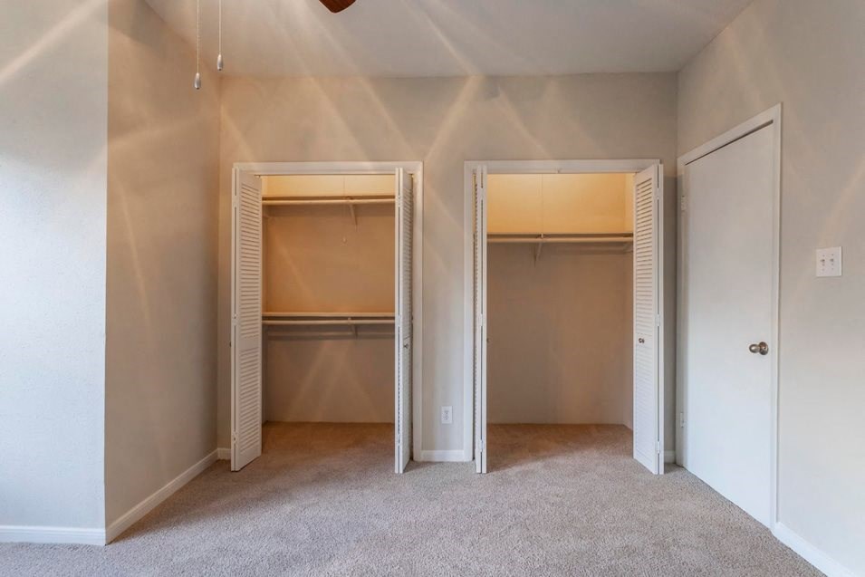 an empty closet in a bedroom with doors open