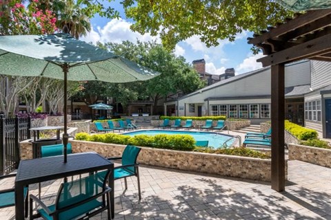 a patio with tables chairs and umbrellas and a swimming pool