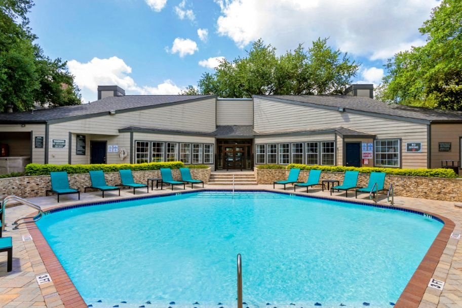 a swimming pool with blue chairs in front of a building