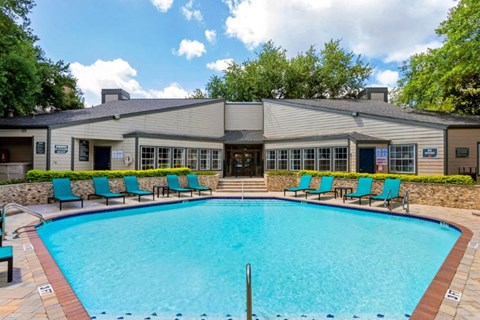 a swimming pool with blue chairs in front of a building