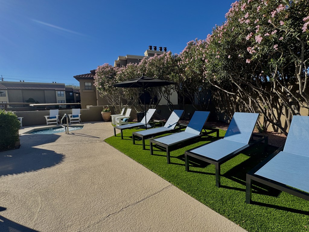 A row of blue lounge chairs are arranged on a concrete patio.