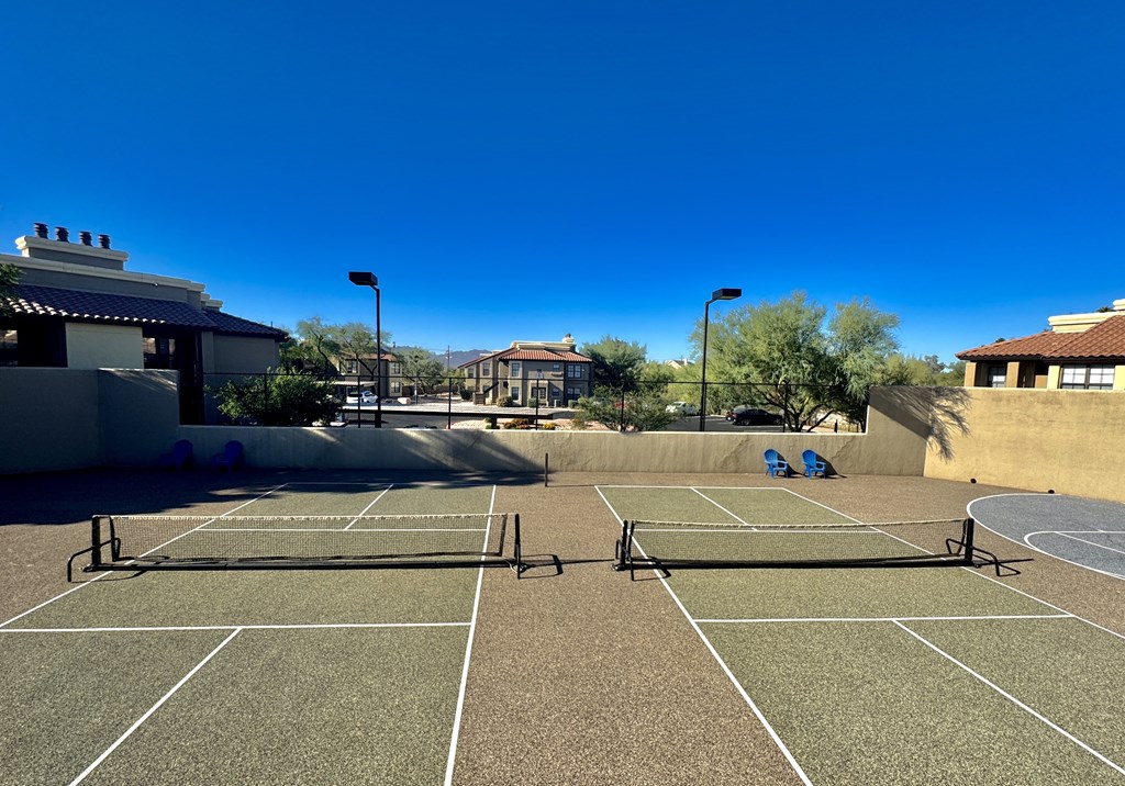 A tennis court with a net and two benches.