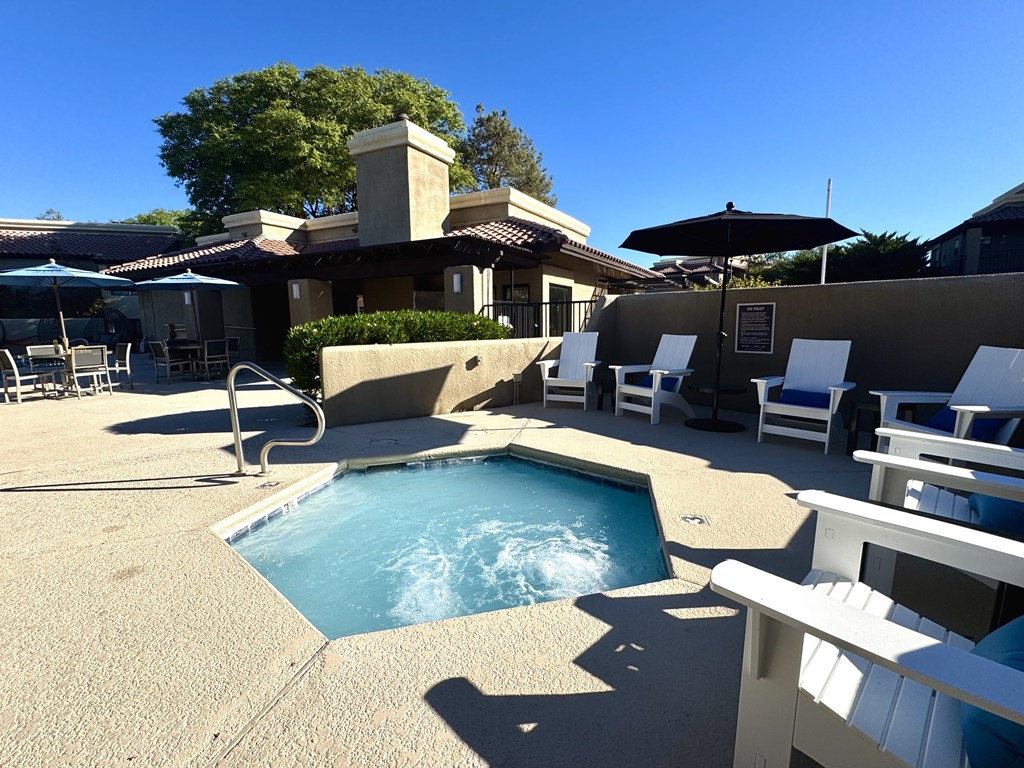 A pool with a white fence and chairs around it.