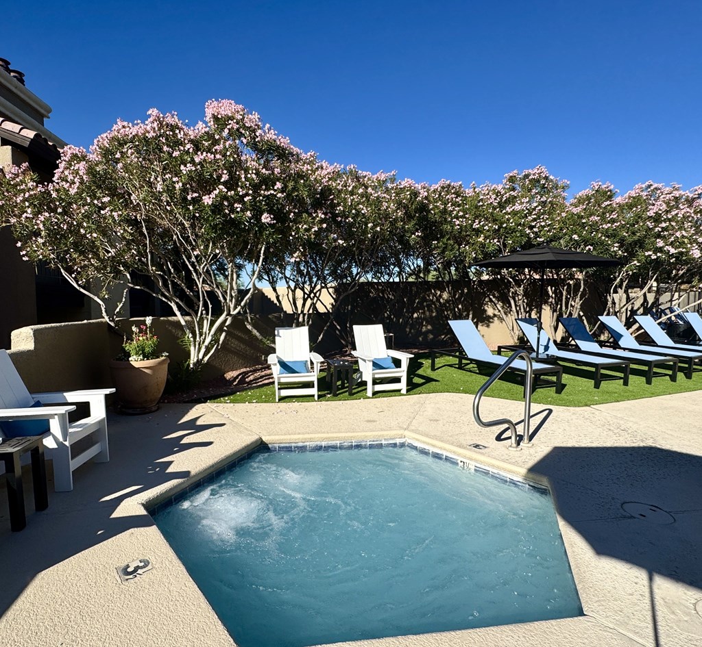 A pool surrounded by chairs and a canopy.