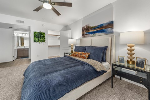 A bedroom with a large bed and a ceiling fan.