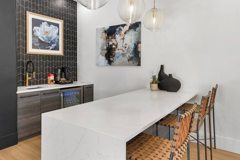 A modern kitchen with a long white table and chairs.