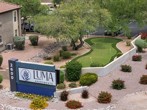 A sign for Luma Apartments is in front of a landscaped area.