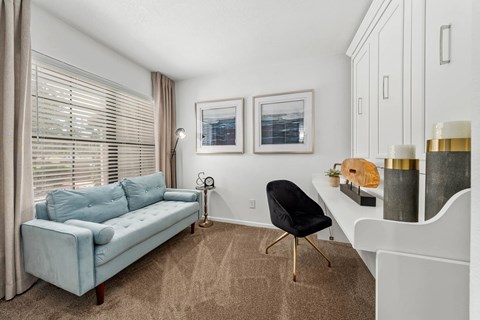 A living room with a blue couch, a chair, and a small table with a plant on it.