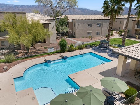 A swimming pool surrounded by palm trees and umbrellas.
