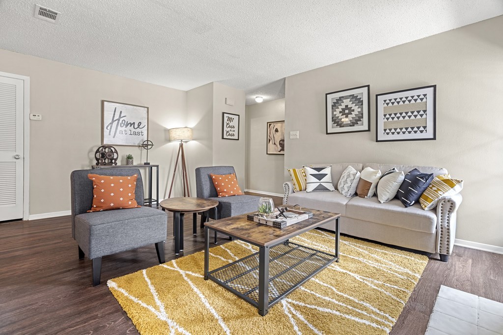 A living room with a grey couch, a coffee table, and a rug.