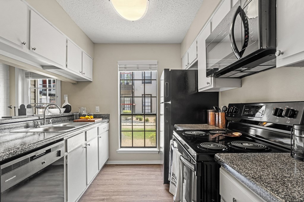 A kitchen with black appliances and white cabinets.