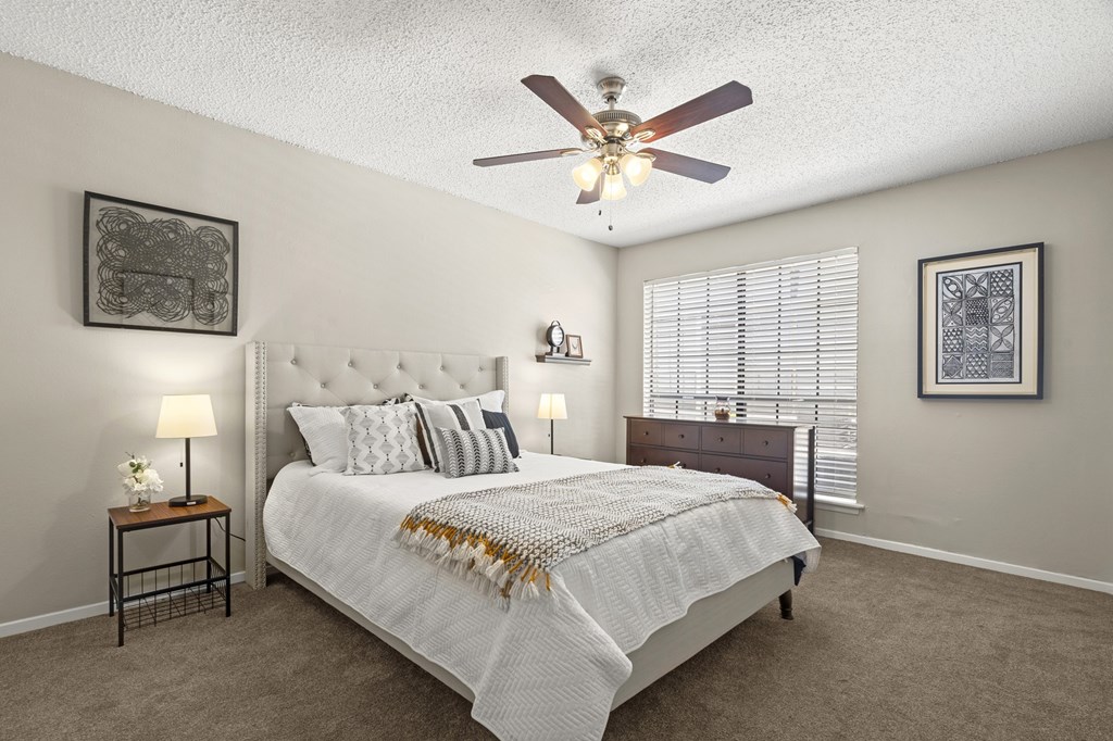 A bedroom with a large bed and a ceiling fan.