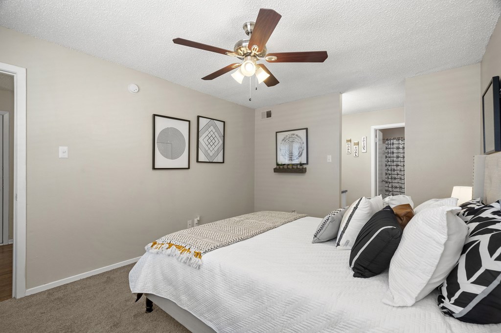 A bedroom with a bed, pillows, and a ceiling fan.