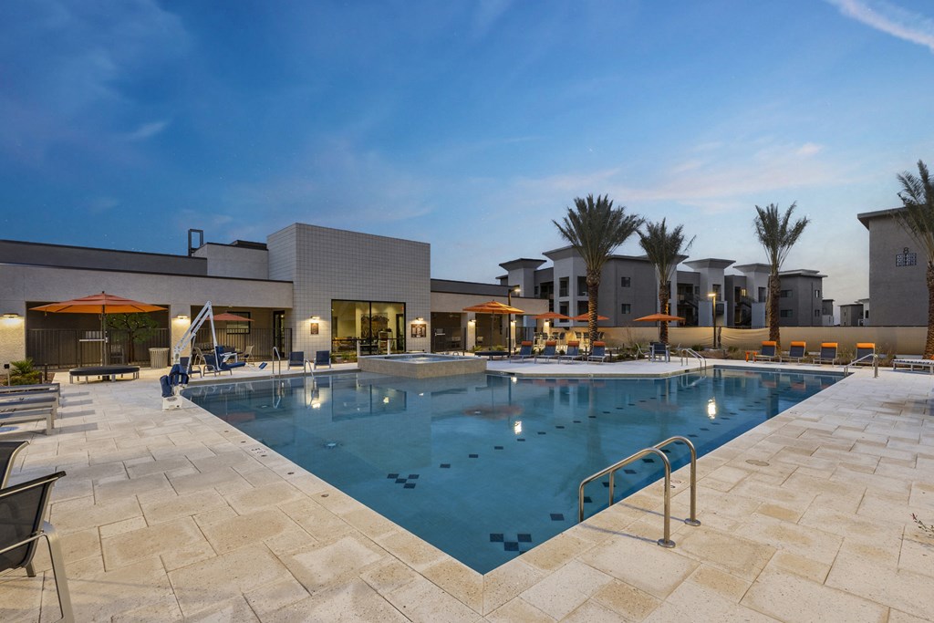 A large swimming pool surrounded by a stone patio and palm trees.