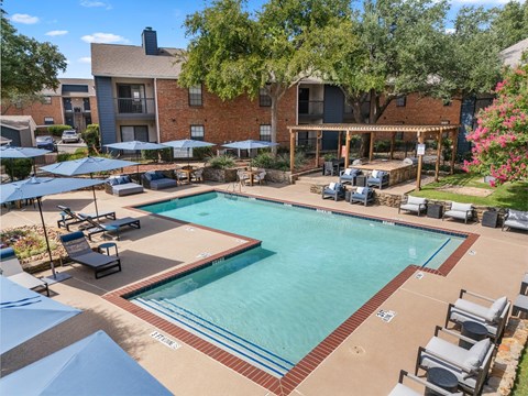 A large swimming pool surrounded by lounge chairs and umbrellas.