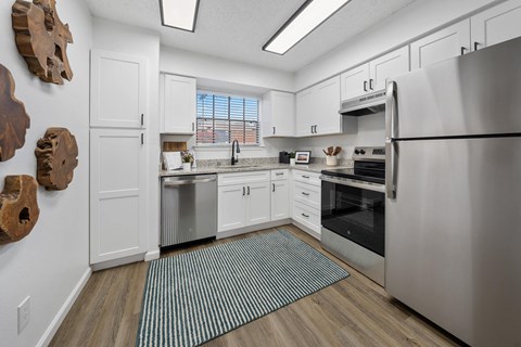 A kitchen with a refrigerator, oven, and sink.