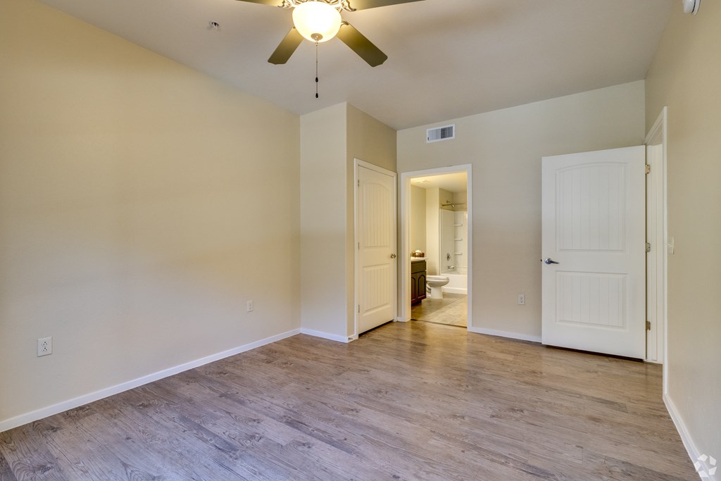 A room with a ceiling fan and light, and a doorway leading to another room.