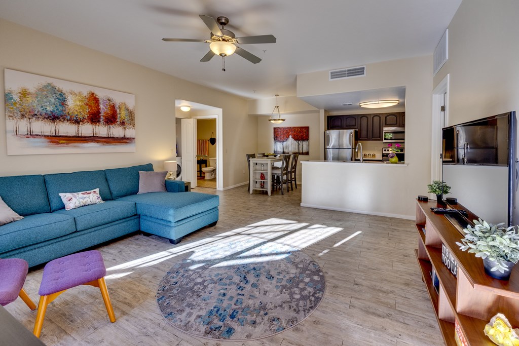 A living room with a blue couch and a painting on the wall.