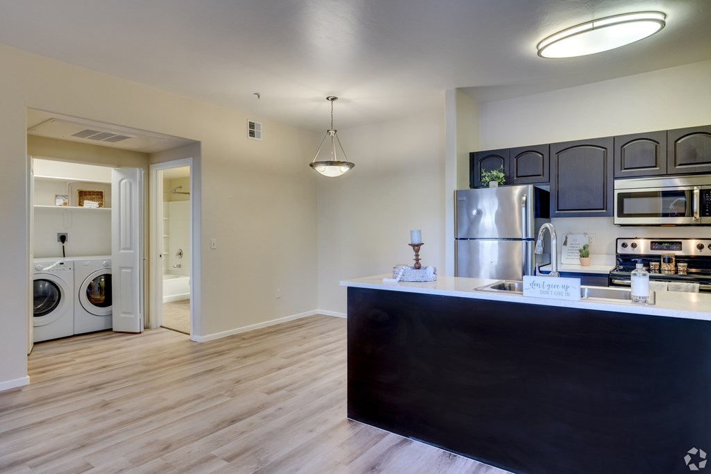 A kitchen with a black counter and stainless steel appliances.