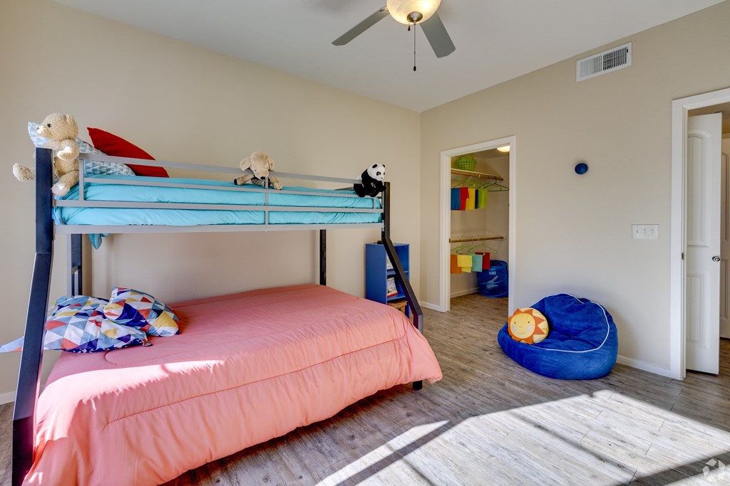 A bedroom with a blue bunk bed and a pink bedspread.