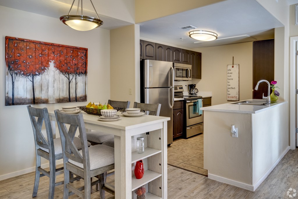 A kitchen with a table and chairs and a painting of trees on the wall.