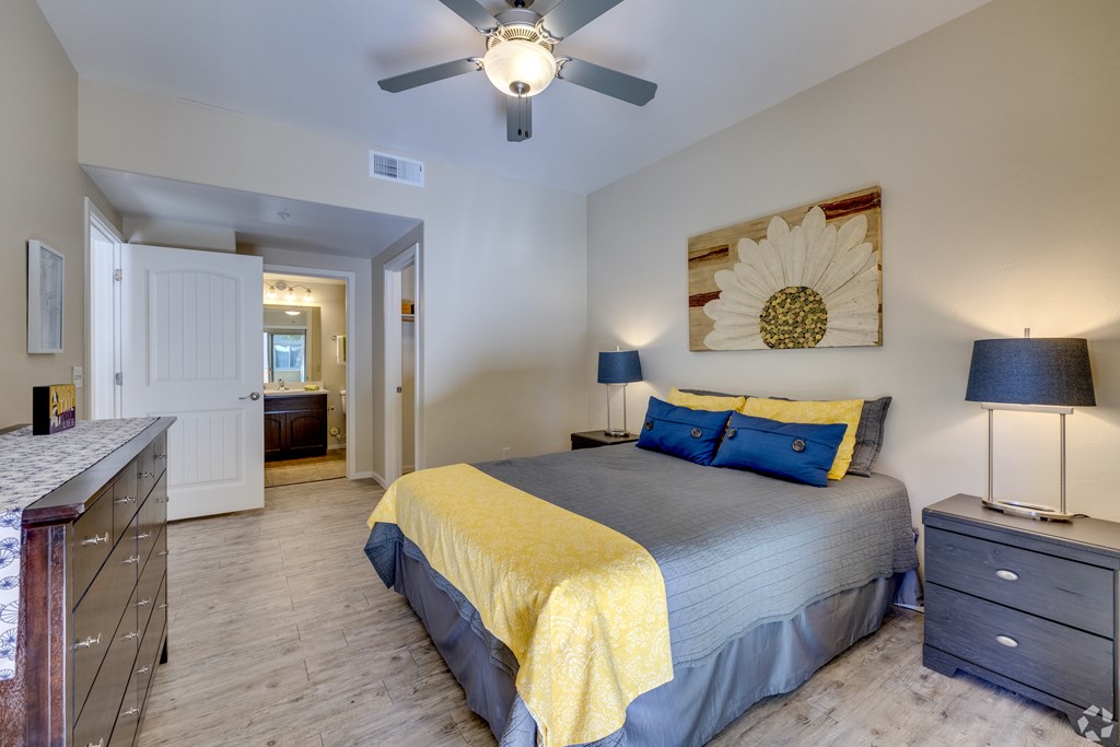 A bedroom with a bed, dresser, and ceiling fan.