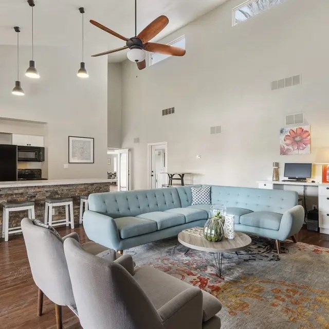 A living room with a blue couch and a ceiling fan.