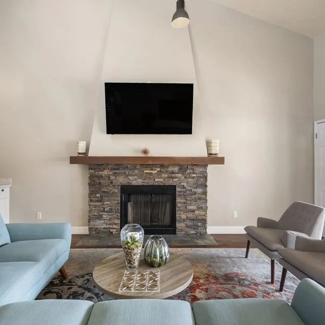 A living room with a fireplace and a flat screen TV mounted above it.