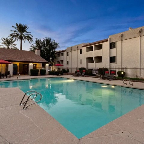A swimming pool in a resort with a building in the background.