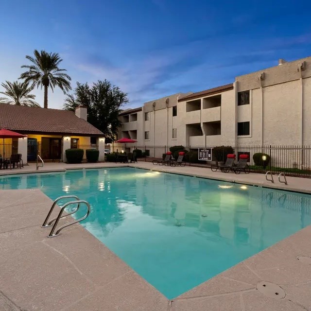 A swimming pool in a resort with a building in the background.