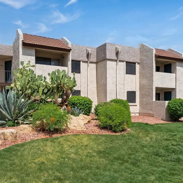 A building with a red tile roof and a well-manicured lawn in front.