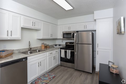A kitchen with white cabinets and a stainless steel refrigerator.