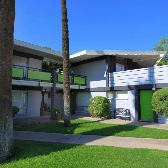 A building with a green door and a bench in front of it.