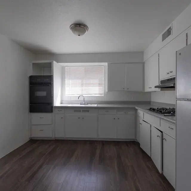 A kitchen with white cabinets and a black fridge.