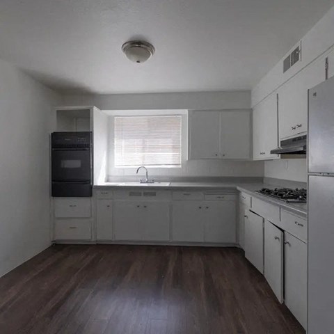 A kitchen with white cabinets and a black fridge.