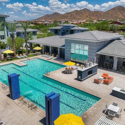 A swimming pool with a yellow umbrella and a building in the background.