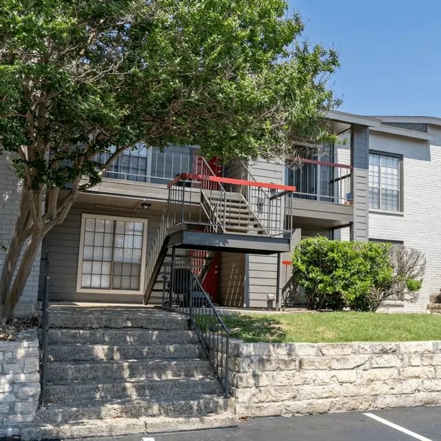 A two-story apartment building with a red staircase.