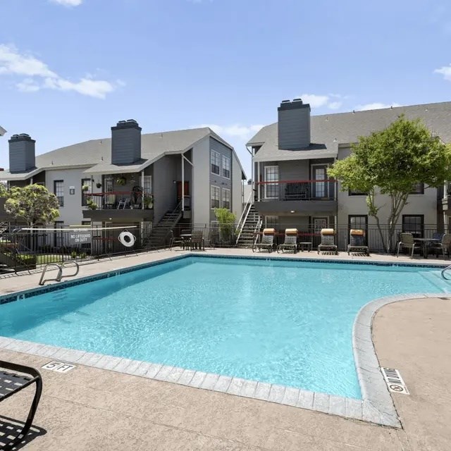 A swimming pool in front of a building with a black fence around it.