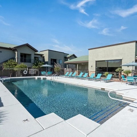 A swimming pool with blue water and lounge chairs.