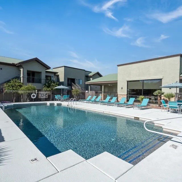 A swimming pool with blue water and lounge chairs.