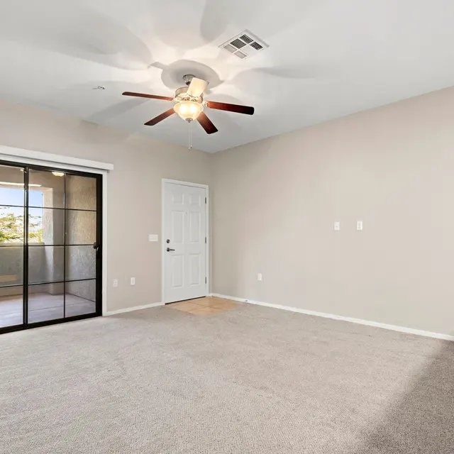 A room with a ceiling fan and a sliding glass door.