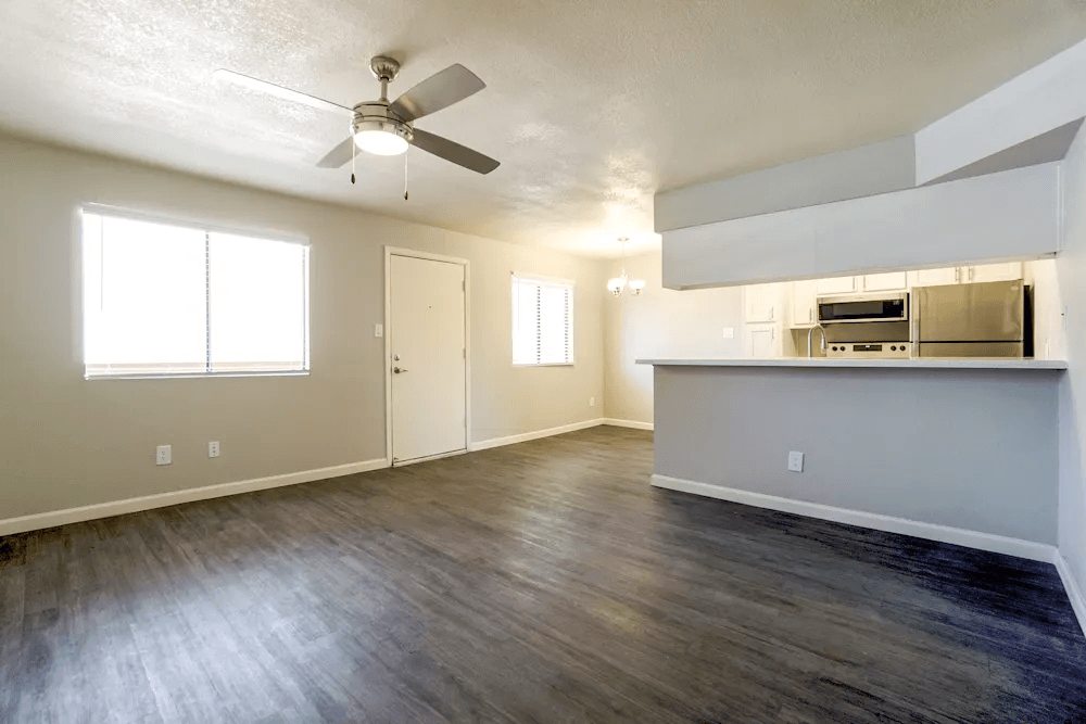 A room with a ceiling fan and wooden flooring.