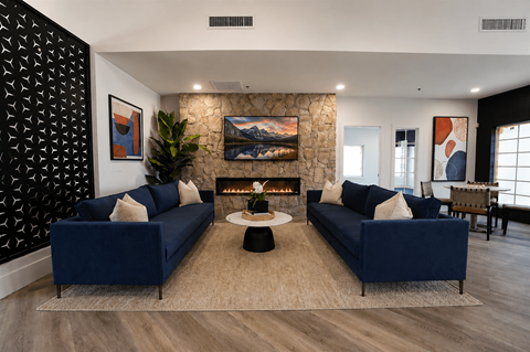 A living room with two blue couches and a fireplace.