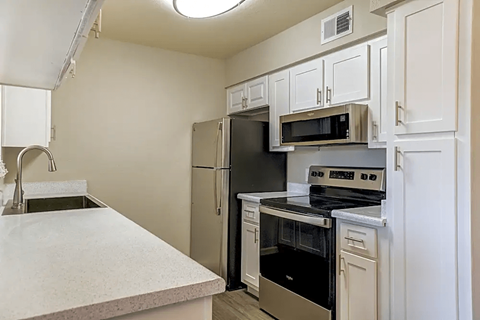 A kitchen with a stainless steel refrigerator, microwave, and oven.