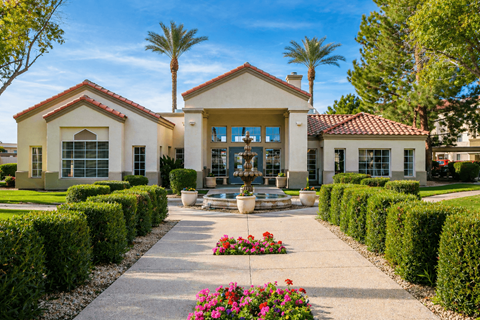 A building with a red tile roof and a fountain in front.