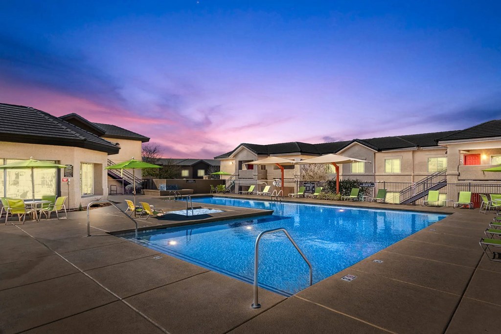 A swimming pool surrounded by lounge chairs and a building in the background.