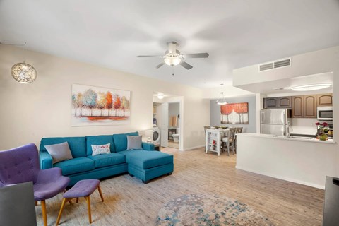 A living room with a blue couch and a ceiling fan.