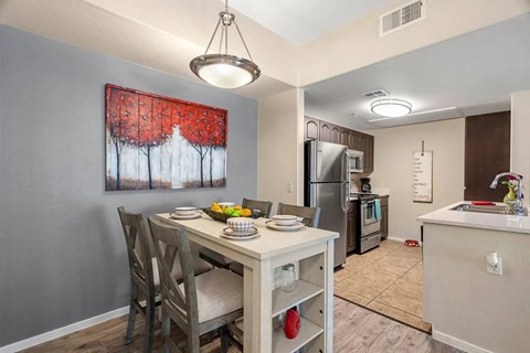 A kitchen with a table and chairs and a painting of trees on the wall.