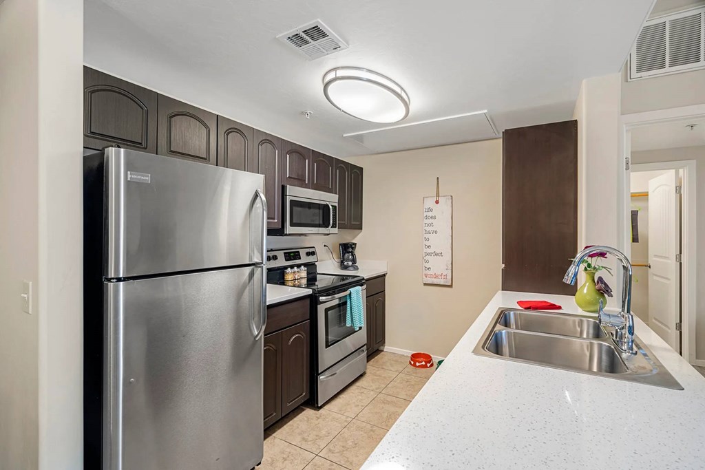 A kitchen with a refrigerator, microwave, oven, and sink.