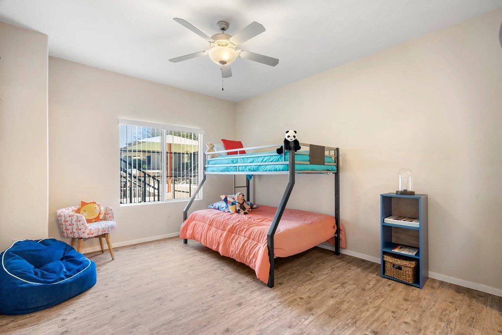 A room with a bunk bed, a chair, a bean bag, and a shelf.
